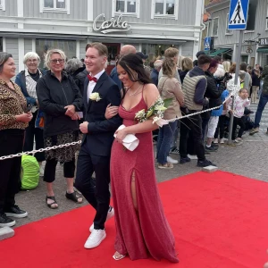 Glittrig röd långklänning med öppen rygg - Säljer en röd långklänning med glittrigt tyg och smala axelband som korsas i ryggen. Klänningen har en slits framtill och en öppen rygg med knytning. Perfekt för bal eller festliga tillfällen. Den är uppsydd! Jag är ca 160 cm lång och bär en 7 cm klack på bilden. Endast använd en gång, frakt tillkommer! 