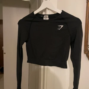Svart långärmad topp från Gymshark - Säljer en svart croppad långärmad topp från Gymshark. Tight och ganska kort i modellen, storlek M ❣️ Lägg gärna ett prisförslag ❤️