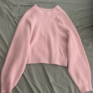 Rosa stickad tröja från ASOS - Säljer en söt rosa stickad tröja från ASOS. Tröjan har en croppad design med långa ärmar och ribbad struktur. Perfekt för kyliga dagar!