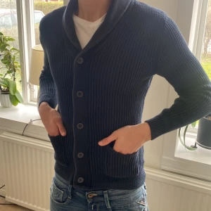 Cardigan mörkblå - Säljer en snygg mörkblå stickad cardigan med knappar framtill och två fickor. 