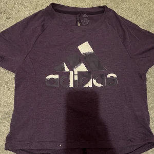 Lila T-shirt  - Lila T-shirt i jätte fin färg från märket adidas. Diskret logga och är lite öppen i ryggen. Jätte fin passform och skick. Sommrig känsla! Sista bilden är färgen i solljus💜Skriv gärna vid frågor! 🤗