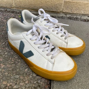 Vita sneakers från Veja - Snygga vita sneakers från Veja med grå detaljer och en kontrasterande gul sula. Skorna har klassisk snörning och rund tå, vilket ger en stilren look. Perfekta för en avslappnad stil. De är avvända men inget större fel på säljs pga för små 💞