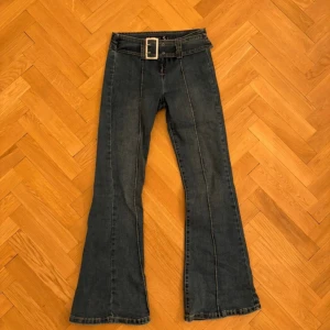Blå bootcut jeans med bälte - Vintage, mörkblå flared jeans med låg midja. Så snyggt och unikt med detaljer som ”bältet” och sömmarna längs med benen! Köpta på Vinted. Står ej för frakt💕