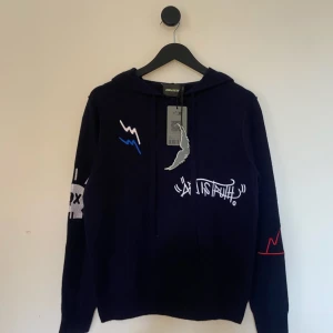 Zadig Voltaire Hoodie - HELT NY! Snygg marinblå hoodie från Zadig & Voltaire med coola grafiska detaljer i vitt, blått och rött. Tröjan har en klassisk huva med dragsko och är perfekt för en avslappnad stil. Den har långa ärmar och en unik design som sticker ut. Perfekt för sommarn och kyliga kvällar då den är gjord i kasmhir! Storlek S men passar Xs. 