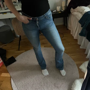 Ljusblå bootcut jeans - Säljer ett par ljusblå jeans med bootcut-modell och klassiska fem fickor. Jeansen har normal passform och stängs med dragkedja och knapp. Perfekta för en avslappnad och trendig look.
