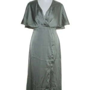 Grön klänning i satin - Superfin klänning i satinmaterial med omlott och korta vida ärmar. Klänningen har en v-ringad halsringning och en slit på ena sidan. Vet ej märket då lappen är borta. Skriv för fler bilder😊Priset kan diskuteras.