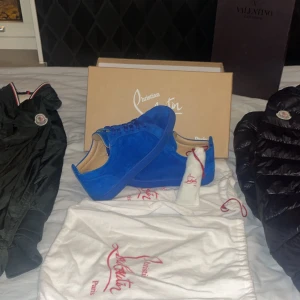 Blå sneakers från Christian Louboutin - Snygga blå sneakers från Christian Louboutin med den ikoniska röda sulan. Skorna har en stilren design med snörning och är tillverkade i ett lyxigt material. Perfekta för att ge din outfit en färgklick.självfallet äkta. Har ni frågor är de bara att hojta till🙌🏻😄dom sitter mer som 41,5 