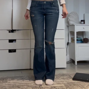 Blå bootcut jeans med slitningar - Super snygga  blå bootcut jeans med slitningar och hål på ena knät. Jeansen har låg midja. Skriv för frågor 