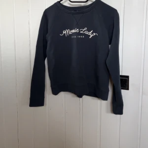 Mörkblå sweatshirt från Morris Lady - Säljer en mörkblå sweatshirt från Morris Lady med vit broderad text på bröstet. Tröjan har rund halsringning och långa ärmar. Perfekt för en avslappnad och stilren look.