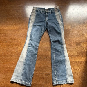 Blå bootcut jeans från Weekday - Säljer ett par blå bootcut jeans från Weekday med kontrasterande ljusa paneler längs sidorna. Jeansen har klassisk femficksdesign, hällor för bälte och dragkedjegylf. Perfekta för dig som gillar en retroinspirerad look. Använda fåtal gånger så mycket bra skick