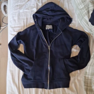 Mörkblå hoodie från 157 - Mörkblå hoodie med dragkedja från lager 157. Tröjan har ett skönt mjukt tyg som man kan ha under hela dagen. Dock så har det ett hål på baksidan av tröjan, som är i mitten åt vänster. Men som inte märks av så mycket. Annars så är den skadefri och om ni har några frågor kan ni bara fråga☺️