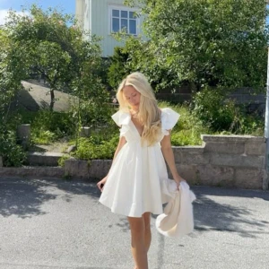 Vit klänning med volangärmar showpo  - Superfin vit kortklänning från showpo med djup v-ringning, volangärmar och öppen rygg med knyt. Tillverkad i ett lätt och luftigt material, perfekt för varma dagar. Aldrig använd 