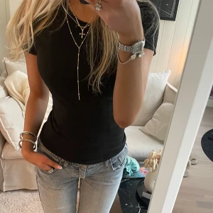 Svart tight t-shirt - Snygg svart t-shirt med korta ärmar och en klassisk rund hals. Perfekt basplagg för alla tillfällen. Enkel och stilren design som passar till det mesta.