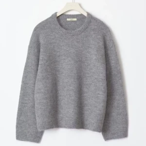 Grå stickad tröja från Zara - Mysig grå stickad tröja från Zara med rund halsringning och långa ärmar. Tröjan har en klassisk passform och ribbade muddar vid ärmslut och nederkant.obs den har ett litet hål på baksidan