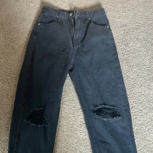 Svarta jeans med hål på knäna - Säljer ett par svarta jeans med raka ben och slitna hål på båda knäna. Snygga High waisted. Det står storlek XXS skulle själv säga storlek S/M. Har själv storlek S och de är för stora på mig!❤️ Längd: ca 105cm  Perfekta för en avslappnad och trendig look. 