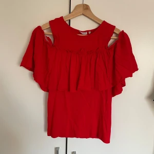 Röd volangtopp från Pigalle - Säljer en röd topp från Pigalle med volangdetaljer och offshoulder-design. Toppen har en lös passform.