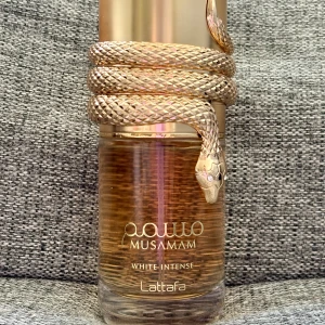 Musamam White Intense från Lattafa - Upptäck Musamam White Intense från Lattafa, en elegant parfym med en härlig sommarvibe. Doften kombinerar träiga och varma kryddiga toner med inslag av kokos, citrus och vanilj. Den har toppnoter av bergamott och apelsin, mellannoter av ylang-ylang och kokos, samt basnoter av sandelträ och mysk. 100 ml, endast testad, kommer i originalkartongen.