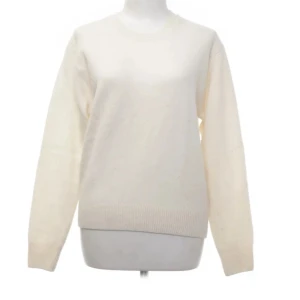 Vit stickad tröja - Säljer en klassisk vit stickad tröja med rund hals och långa ärmar. Perfekt för kyliga dagar och enkel att matcha med olika outfits. Tröjan har ribbstickade muddar vid ärmslut och nederkant.