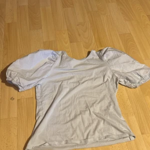 Vit topp med puffärmar - Säljer en ljusblå topp med stora puffärmar och rund halsringning. Toppen har en enkel design men är ändå ett statement-plagg tack vare de voluminösa ärmarna. Perfekt för dig som vill ha något stilrent men ändå trendigt.
