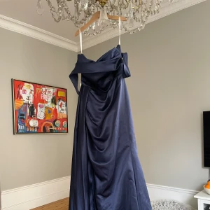 Marinblå satin balklänning - Säljer min balklänning som kom till användning en gång, därav är den som ny. Klänningen är specialsydd i midja och längd och sitter perfekt på mig som är ca 170 cm lång. Skriv för frågor eller fler bilder!🤗