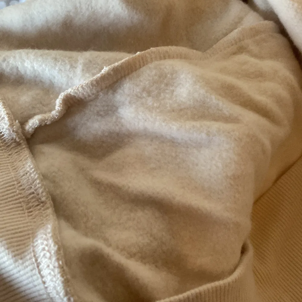 Säljer en beige hoodie med huva och dragsko från märket C. Tröjan har långa ärmar, ribbade muddar och är gjord i mjukt, fleeceliknande material på insidan. Perfekt för en avslappnad stil.. Neuletakit & Villapaidat.