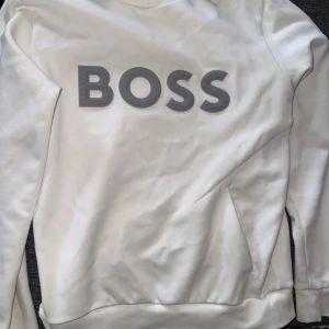 Vit sweatshirt från BOSS  - Snygg vit sweatshirt från BOSS med stor grå 3D-logga framtill. Tröjan har oxå en ficka vid magen, använd ca 10 gånger. Köpt för 1800