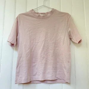 Ljusrosa t-shirt från Gina Tricot - Enkel och stilren ljusrosa t-shirt från Gina Tricot, basically basics-kollektionen. T-shirten har rund halsringning, korta ärmar och är gjord i mjuk bomull. Perfekt för en clean och avslappnad look.