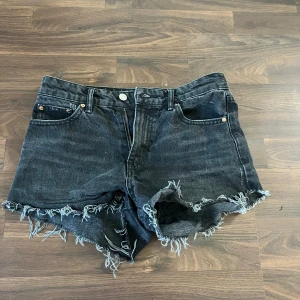 Svarta jeansshorts med fransig kant - Svarta jeansshorts från Perfect Jeans med rå, fransig kant och klassisk femficksdesign. Shortsen har normal passform och bälteshällor, aldrig använt . Materialet är slitstarkt denim och färgen är mörksvart.