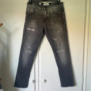 Replay Jeans grå - Snygga grå jeans från Replay, modell MickyM med slim tapered fit. Jeansen har slitna detaljer och en tvättad look som ger en cool vibe. Klassisk femficksmodell med dragkedjegylf och Replay-logga vid fickan. Perfekta för dig som gillar streetstyle.