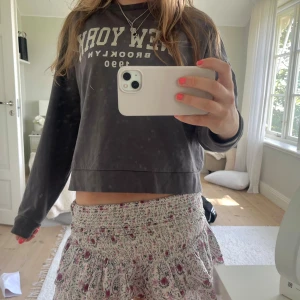 Grå sweatshirt/collegetröja - Säljer en mörkgrå sweatshirt med trycket 'New York Brooklyn 1990' framtill. Tröjan har lång ärm, rund hals och är i mjuk bomull. Perfekt för en chill och avslappnad stil. Strl XS, fint skick