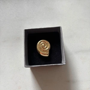 Guldig snäckring  - Säljer en fin guldring. Vet inte om den rostar eller om man blir grön av den. Aldrig använd. Den är justerbar längst ner. OBS! Asken medföljer ej! Läs gärna min bio💕