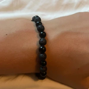Pärlarmband  - Stilrent armband med svarta pärlor i en mix av blanka och matta lavastenar. Elastiskt band gör det enkelt att ta på och av. Perfekt accessoar för dig som gillar en minimalistisk och cool look.