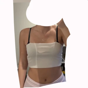 Vit ribbad croppad linnetopp H&M - Vit croppad linnetopp från H&M i storlek M. Toppen är ribbad med smala axelband och har en enkel, stilren look som passar perfekt till jeans eller kjol. Materialet är mjukt och stretchigt för en bekväm passform. Passar M och S. Använd 1 gång. 