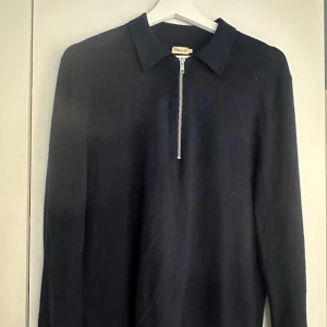 Mörkblå/navy tröja Filippa K half zip - Svart stickad tröja från Filippa K med klassisk krage och silverfärgad half zip-dragkedja framtill. Långärmad modell i mjukt material som ger en clean och stilren look. Perfekt för dig som gillar minimalistisk stil. Ordinariepris 1200 kr.