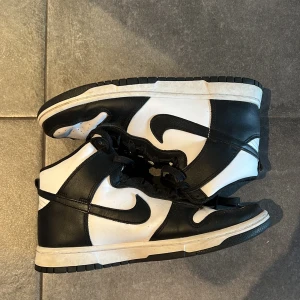 Nike Dunk High svartvita sneakers - ASSSSNYGGA Svartvita Nike Dunk High sneakers med klassisk design och högt skaft. Skorna har svart swoosh, svarta snören och detaljer i svart och vitt skinn. Yttersulan är svart och vit, och ovandelen har perforeringar för extra ventilation. Perfekta för dig som gillar streetwear. Storlek 42.5 passar om du är 43 eller 42, kostar 1 500 nyskick o är i princip nyskick!