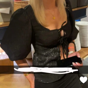 Glittrig fest topp - Svart glittrig topp med knyt detaljer på framsidan och söta ”puff ärmar” från H&M i storlek XS🌺