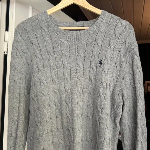 Grå kabelstickad tröja Polo Ralph Lauren - Kabelstickad grå tröja från Polo Ralph Lauren med klassisk rund halsringning och broderad logga på bröstet. Nypris ungefär 1600 kronor. Skriv om ni har frågor eller prisförslag🙌🏽