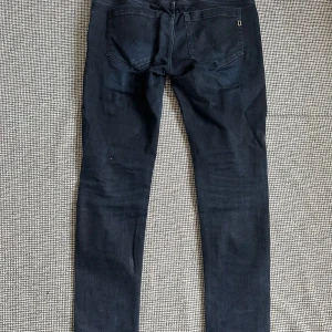 Mörkblå Dondup jeans herr, stl 33 - Säljer ett par mörkblå Dondup jeans i klassisk femficksmodell. Jeansen har en slim passform med raka ben och snygga detaljer vid fickorna. Materialet är mjukt och stretchigt för extra komfort. Perfekta för dig som gillar stilrena och moderna jeans. Skriv vid frågor eller andra funderingar! 