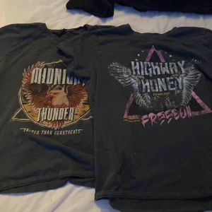 Svarta t-shirts med örntryck - Två svarta t-shirts med coola tryck framtill. Ena har texten 'MIDNIGHT THUNDER' och en stor örn i brunt och beige, den andra har 'HIGHWAY HONEY FREEDOM' med en grå örn och lila detaljer. Båda är kortärmade och har en klassisk passform. Perfekta för dig som gillar rockig stil.