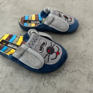 Färgglada tofflor med musmotiv Gezer Kids - Mjuka och mysiga tofflor från Gezer Kids med broderat musansikte framtill och söta öron. Sulan har färgglada ränder i blått, gult, brunt och grått. Perfekta för att liva upp vardagen hemma! Priset går att diskutera!