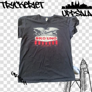 Svart Sko Uno t-shirt med tryck - Svart t-shirt från Sko Uno med coolt örntryck och rödvit logga på bröstet. Klassisk passform och rund halsringning, perfekt för dig som gillar streetwear och vill sticka ut med en unik Stockholm-vibe.