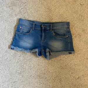 Blå lågmidjade  jeansshorts med fransig kant - Snygga blå jeansshorts, låg midja med klassisk femficksdesign och fransig kant nertill. Shortsen har normal passform, bälteshällor och lätt slitna detaljer för en avslappnad look. Perfekta till sommaren och lätta att matcha med allt. Står strl 158 men passar verkligen xs och s utan att sitta för tajt och täcker där dom ska täcka- kan skicka bild privat hur dom sitter på mig! Skriv för fler frågor o bilder osv. Kolla in mina andra annonser- pris går typ alltid att diskutera!🙌😇