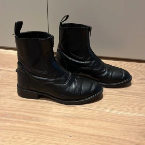 Svarta ridskor/stallskor - Snygga svarta ridskor som funkar att rida i och ha i stallet. De är i gott skick förutom något litet märke som man kan se på bild 5!