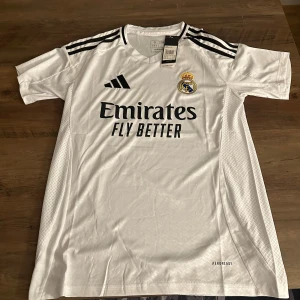 Real Madrid hemmatröja2024/25 från Adidas - Säljer en vit Real Madrid hemmatröja säsongen 24/25 från Adidas. Materialet är lätt och andas, perfekt för fotbollsträning eller match.