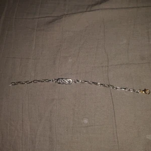 Silverfärgat armband med infinity-länk - Snyggt armband i silverfärg med en infinity-symbol i mitten och grova länkar. Låset är i guldton och ger en cool kontrast till resten av armbandet. Perfekt accessoar för dig som gillar stilrena detaljer med en twist.
