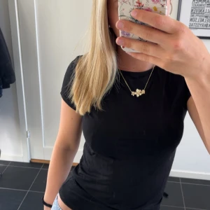 Svart topp med rosett i ryggen - Säljer en svart kortärmad topp med snygg öppen rygg och stor rosett i satinband baktill. Toppen har en tight passform och är perfekt för dig som vill ha något stilrent men ändå med en twist. Superfin att matcha med jeans eller kjol. Prislappen kvar, aldrig använd💓