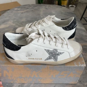 Golden Goose vita sneakers med glitter - Snygga vita sneakers från Golden Goose med silverglittrig stjärna på sidan och svart glitter på hälen. Helt nya 