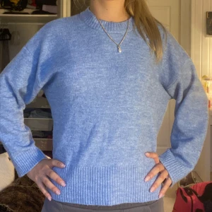 Ljusblå stickad tröja med ribbade detaljer - Supermysig ljusblå stickad tröja med rund hals och breda ribbade muddar vid ärmslut och nederkant. Tröjan har en relaxed passform och är perfekt för kyliga dagar. Enkel och stilren design som är lätt att matcha med jeans eller kjol. Kan se skrynklig ut på bild men det är bara för att den legat i min garderob länge ihoptryckt men går lätt att stryka. Passar som en S