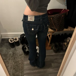 True religion jeans - Snygga mörkblå jeans med bootcut och låg midja. Byxorna har dekorativa sömmar och knappar på bakfickorna. Perfekta för en avslappnad stil.💕
