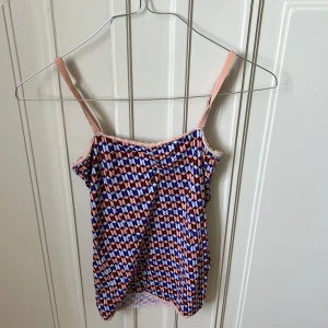 Mönstrad linnetopp från Scotch & Soda - Säljer en färgglad linnetopp från Scotch & Soda med geometriskt mönster i rosa, blått och vitt. Toppen har tunna justerbara axelband och en söt spetskant upptill. 